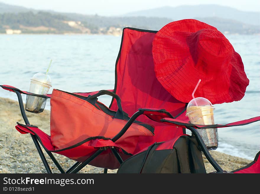 The red chairs on the beach with red hat. The red chairs on the beach with red hat