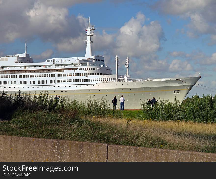 People along the river watching a beautiful passenger ship passing by. People along the river watching a beautiful passenger ship passing by