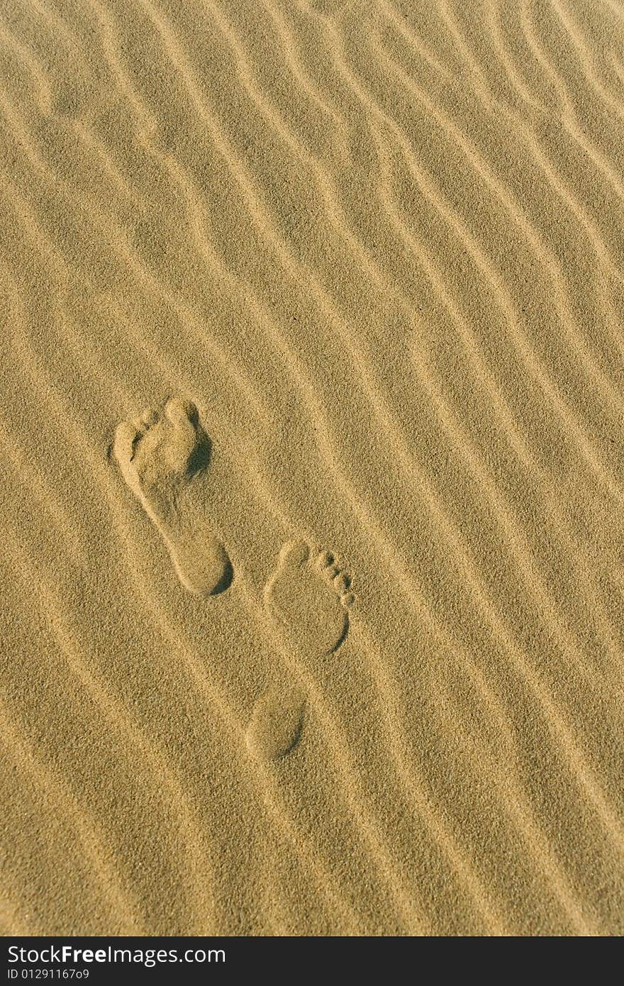 Two footprints on the wavy sand