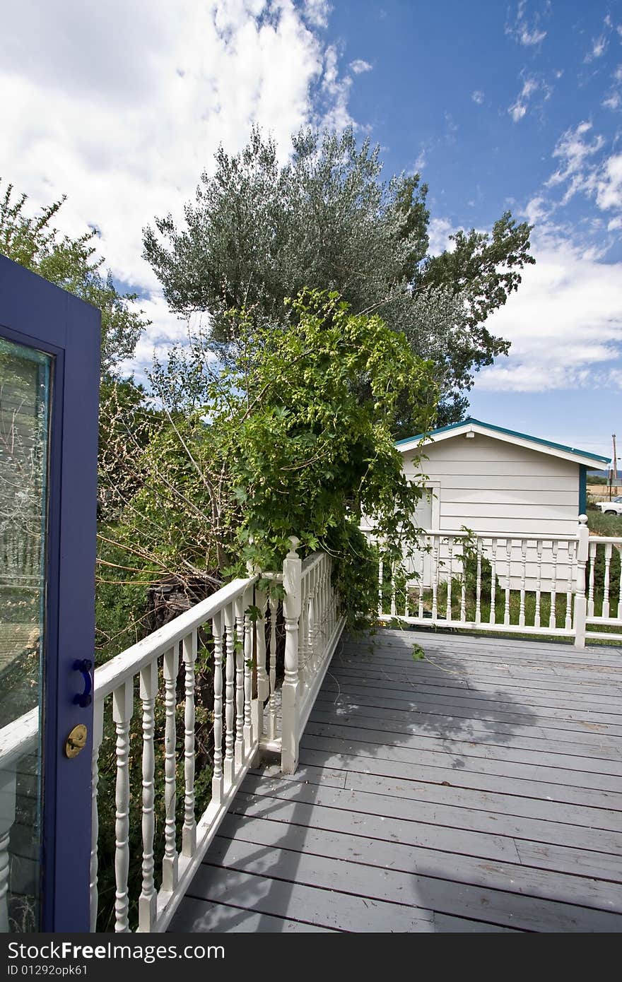 View of deck with wood railing and green shrubs. View of deck with wood railing and green shrubs