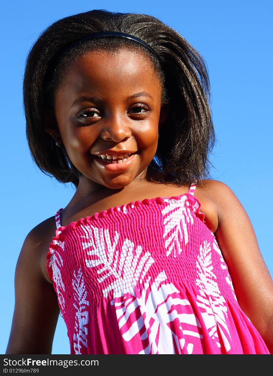 Young girl smiling with blue sky background.