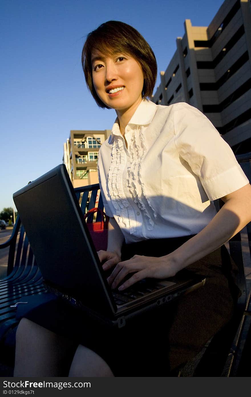 Smiling Woman Works on Laptop - Vertical