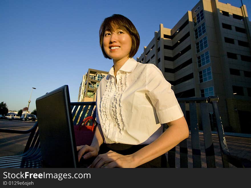 Smiling woman works on laptop while smiling at camera. Horizontally framed photo. Smiling woman works on laptop while smiling at camera. Horizontally framed photo.