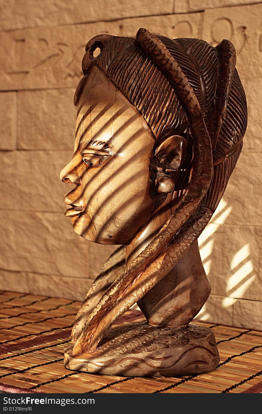 Ancient wooden sculpture from Africa on a sunlight. A head of the woman.