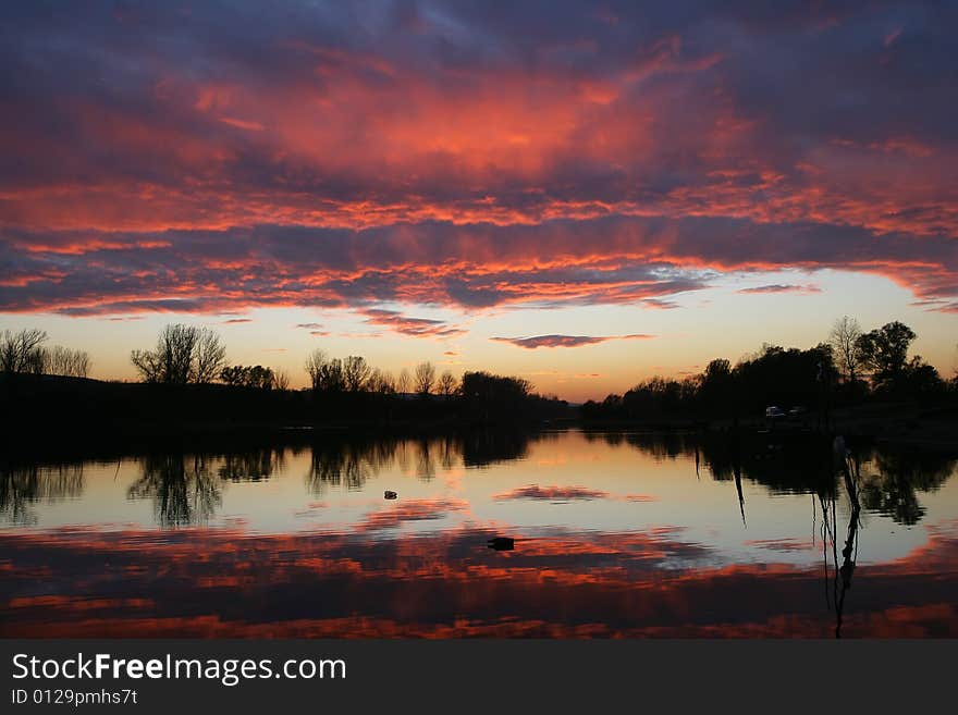 Small river island reflecting itself on the water in the sunset. Small river island reflecting itself on the water in the sunset