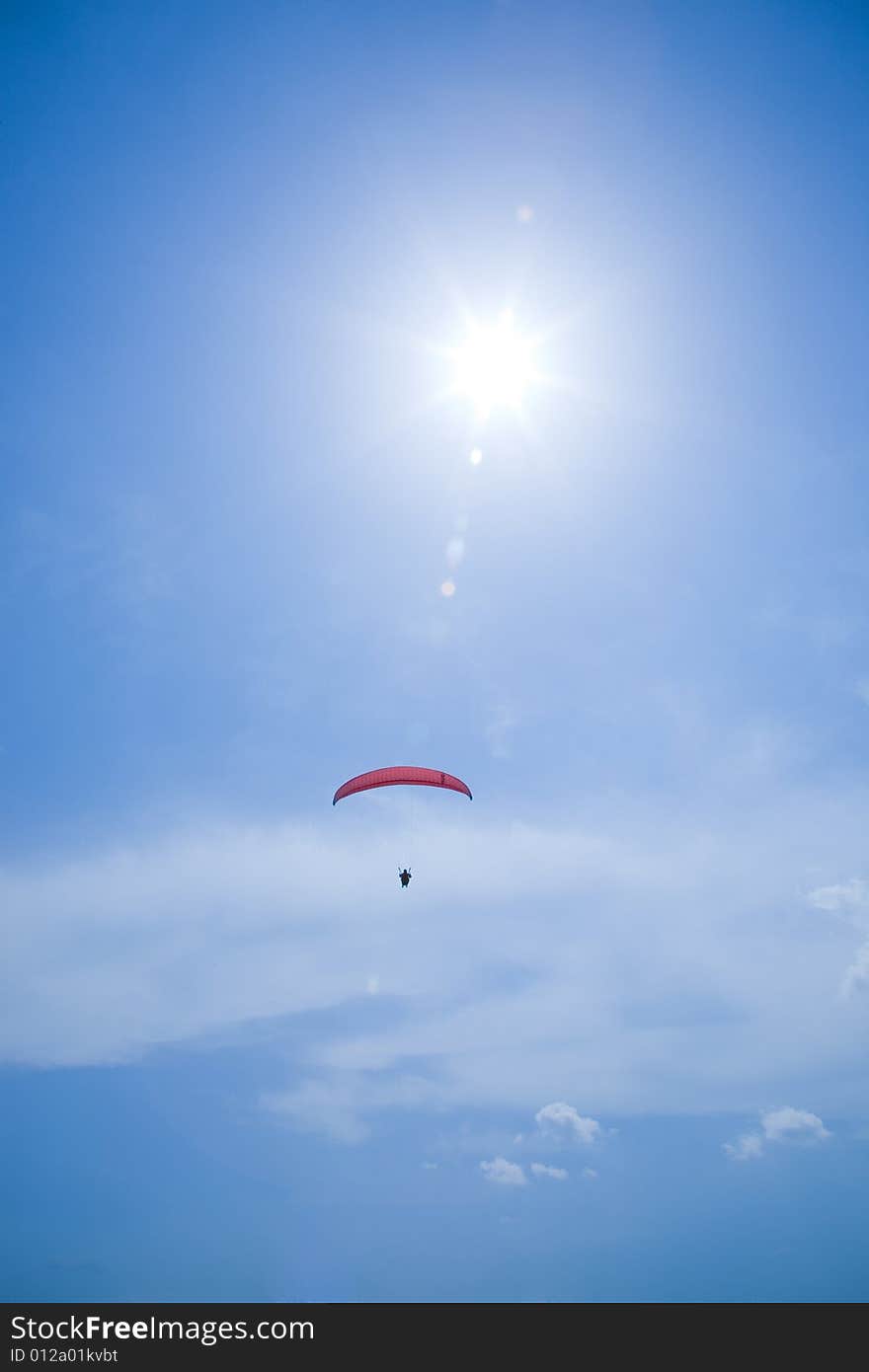 Silhouette of a parachutist with red parachute in blue sky