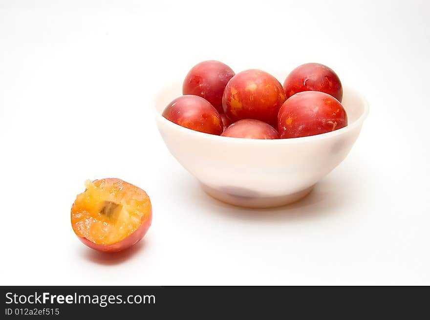 Plums at bowl and  one plum on white background