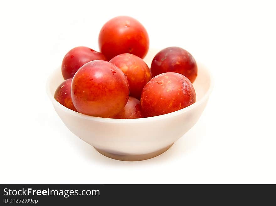 Plums at bowl on white background