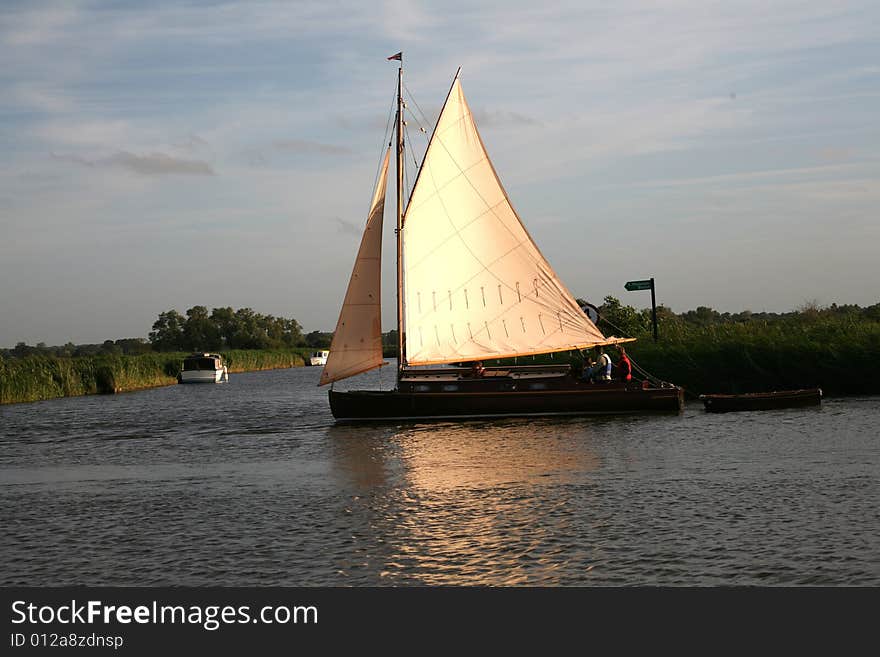 The setting sun lights up the sails of a boat heading home. The setting sun lights up the sails of a boat heading home