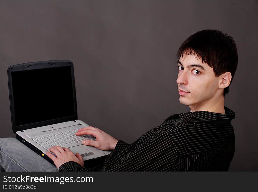 Casual young man sitting with laptop