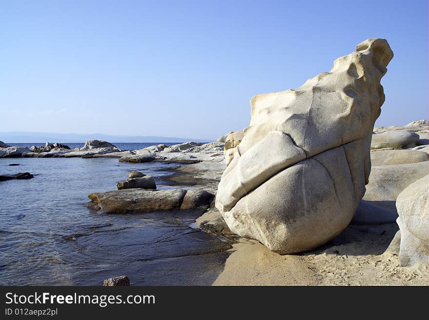 Unusual rock stands by the sea on the beach during sunset. Unusual rock stands by the sea on the beach during sunset