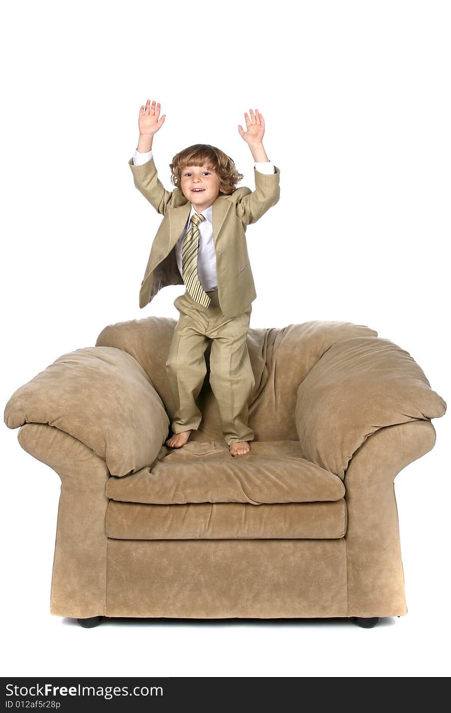 Boy in tan suit jumping on chair. Boy in tan suit jumping on chair