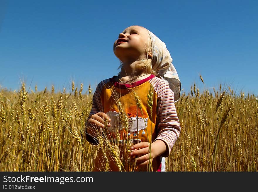 Girl in wheat field looks at sky