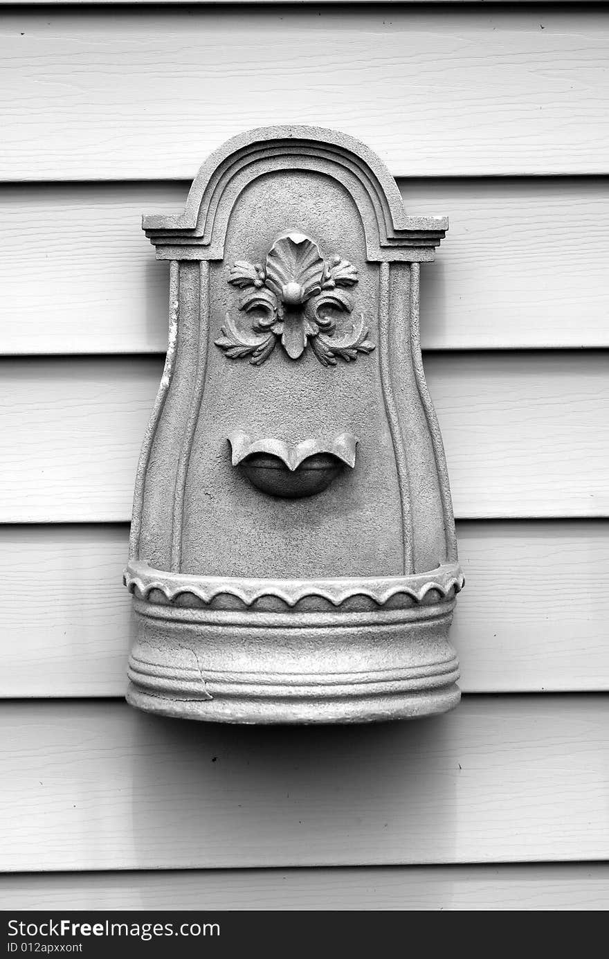 A simple, stone wall fountain shot in black and white.