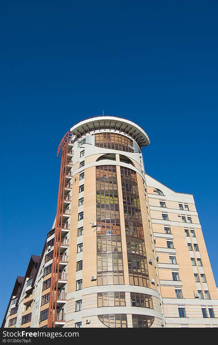 New modern brick multistory house on deep blue sky background in three colors: red, yellow, grey.