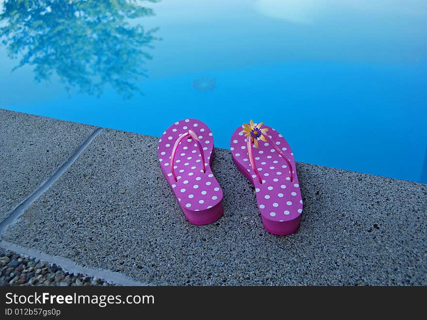 Pair of flip-flops at the edge of the pool. . Pair of flip-flops at the edge of the pool.