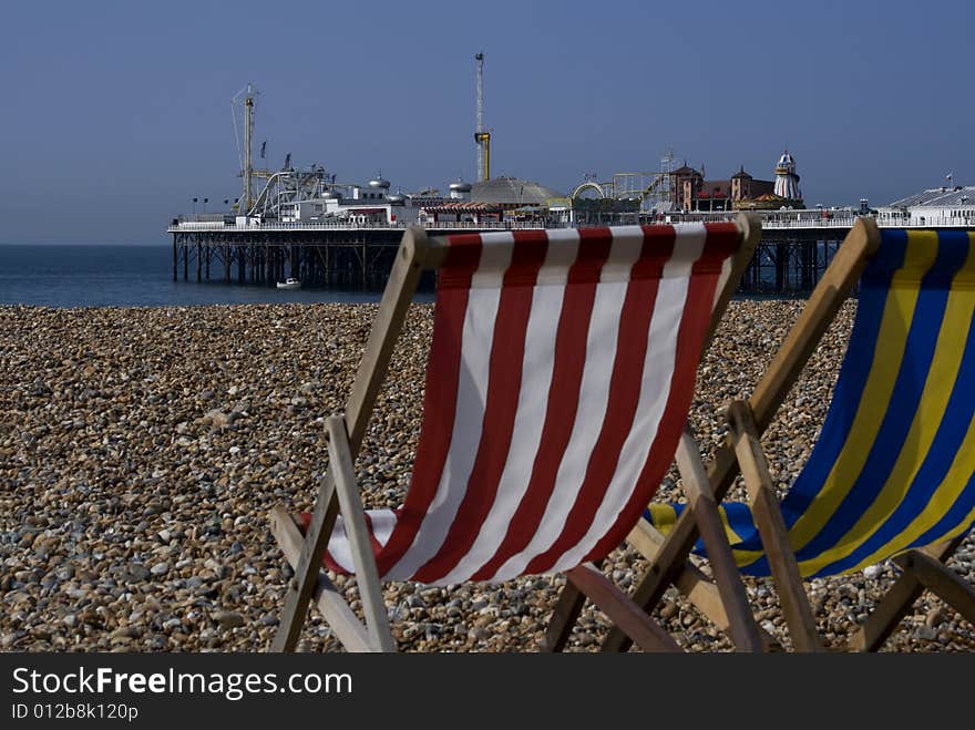 Pair of deck chairs facing out at brighton pier on hot summers day