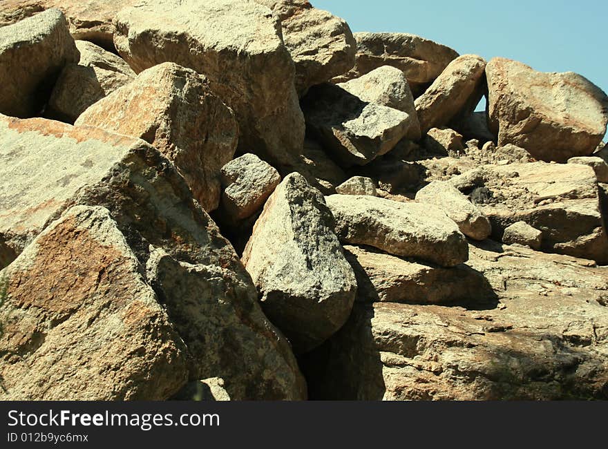 A pile of rocks and boulders in the morning sun, against a clear blue sky. A pile of rocks and boulders in the morning sun, against a clear blue sky