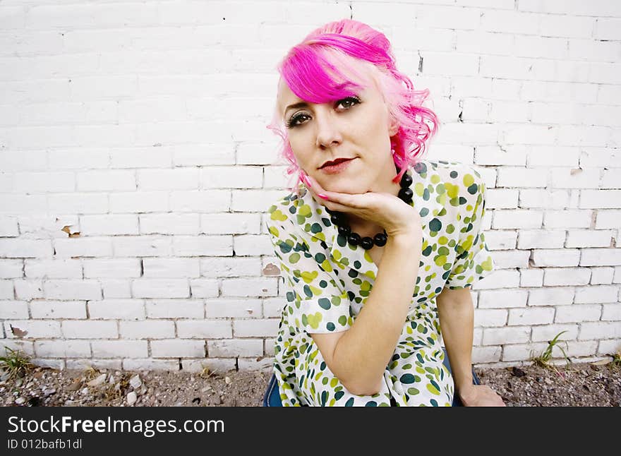 Woman with pink hair wearing polka dot dress in alley