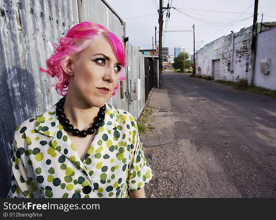 Woman with pink hair wearing polka dot dress in alley. Woman with pink hair wearing polka dot dress in alley