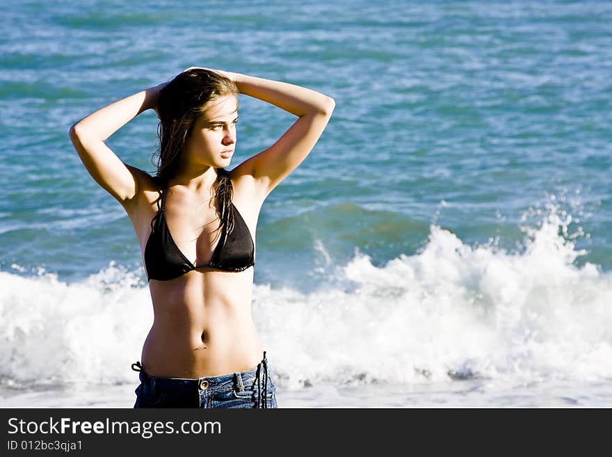 Young beautiful model posing with the ocean as background. Young beautiful model posing with the ocean as background