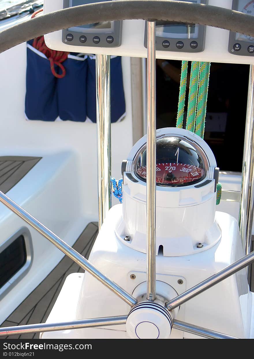 The sail boat wheel and compass close up.