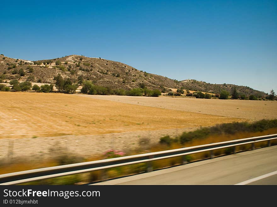 This view from road to dry landscape with hills far away