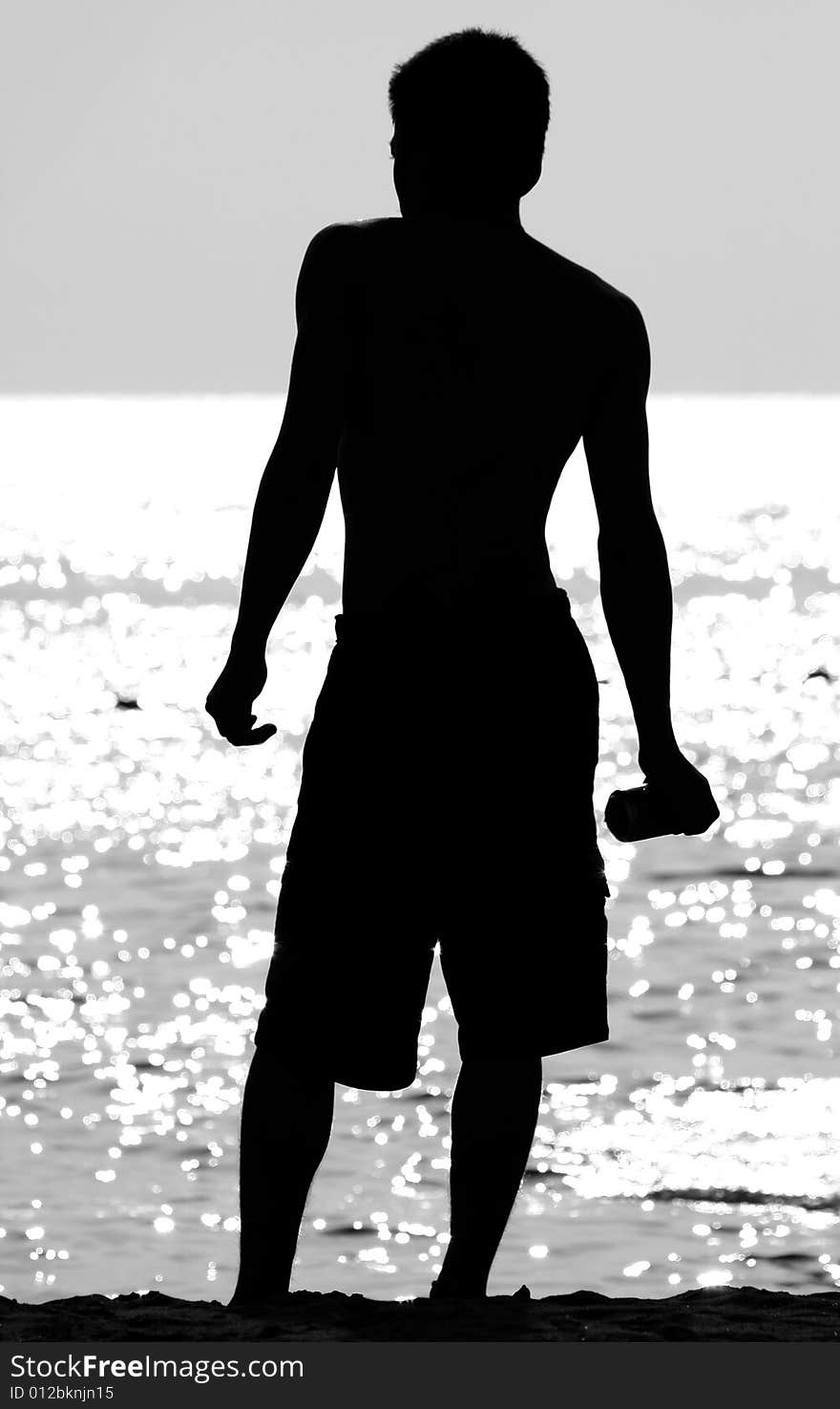 A black and white photograph of a young man standing at the sea shore. A black and white photograph of a young man standing at the sea shore.