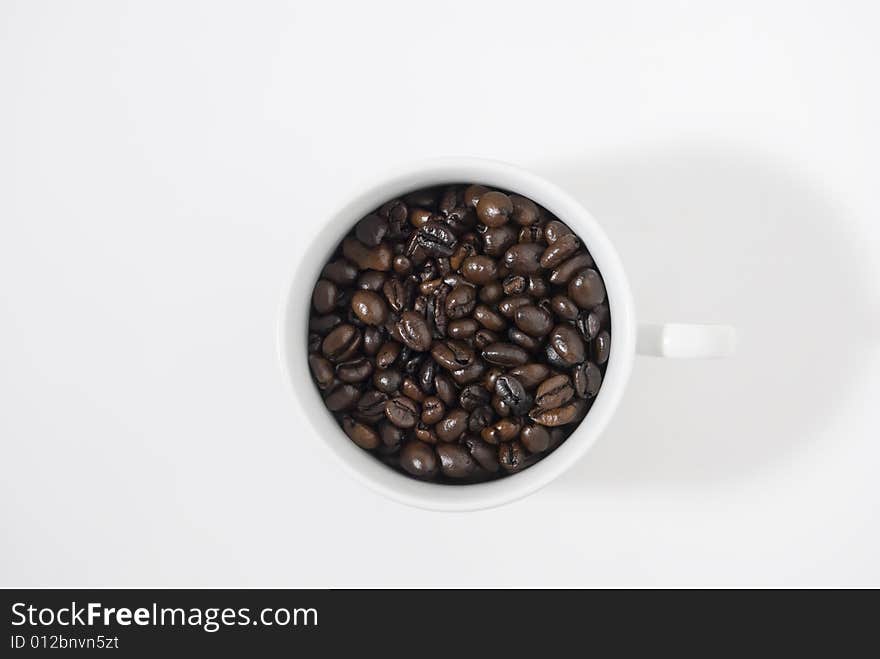 Closeup shot of coffee beans in cup, shot against white background