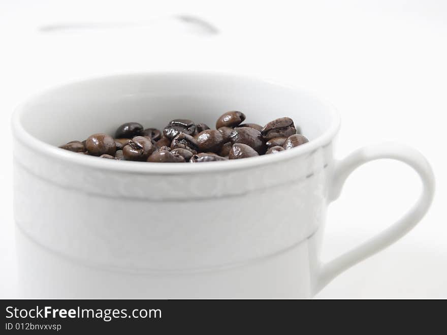 Closeup shot of coffee beans in cup, shot against white background