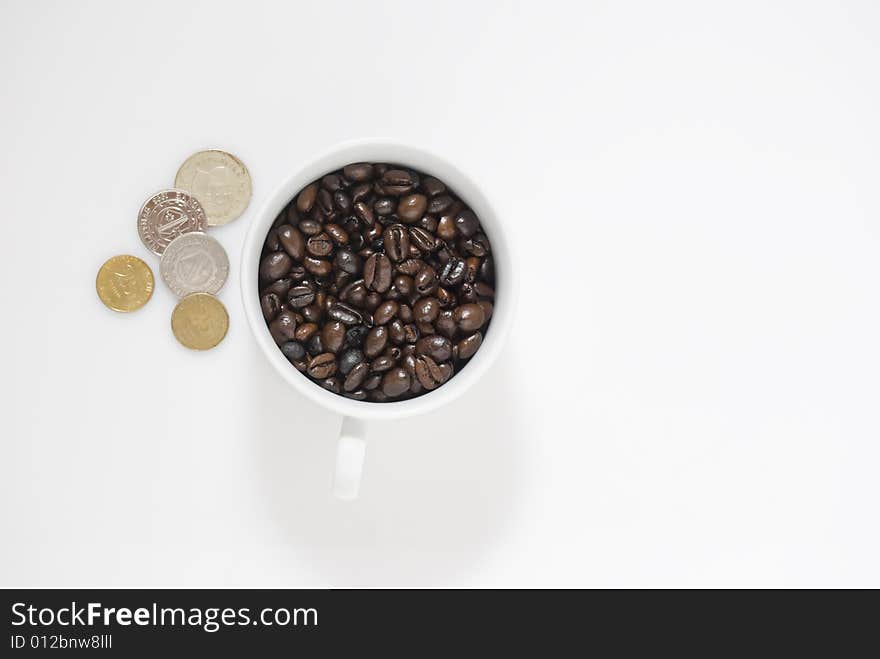 Closeup shot of coffee beans in cup and Philippines coins, shot against white background