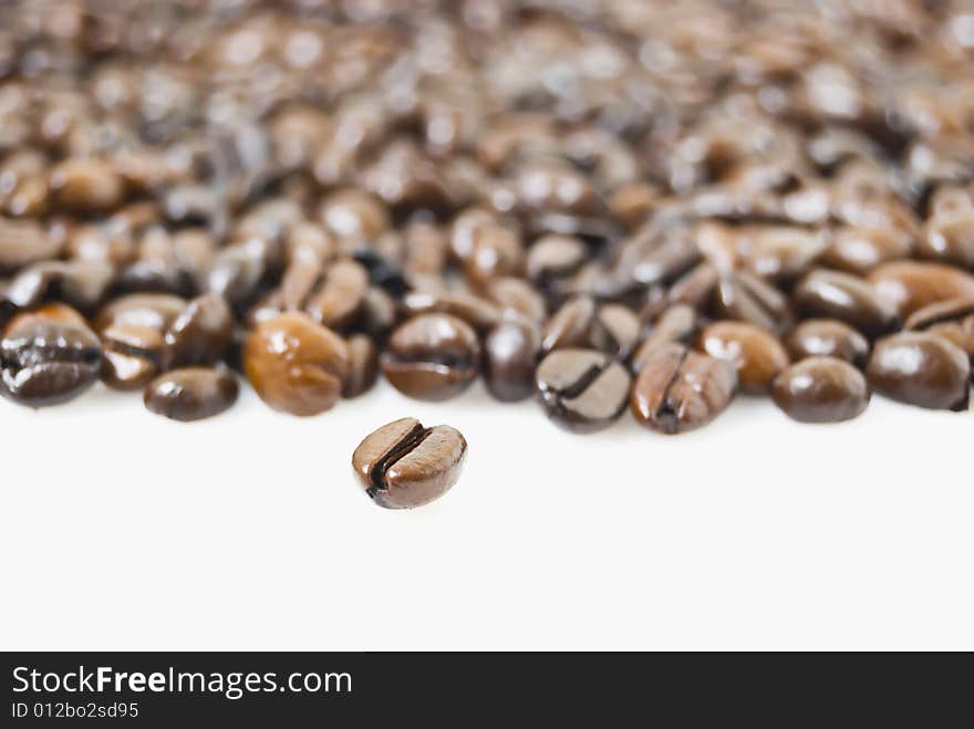 Closeup shot of coffee beans against white background, focus is on bean at foreground