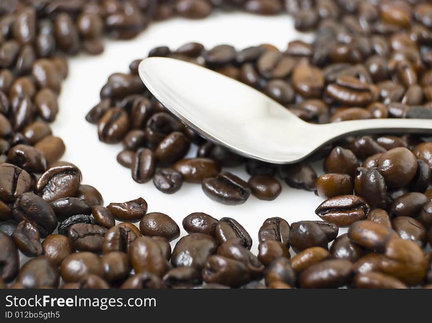 Closeup of coffee beans framing letter C; teaspoon on coffee beans