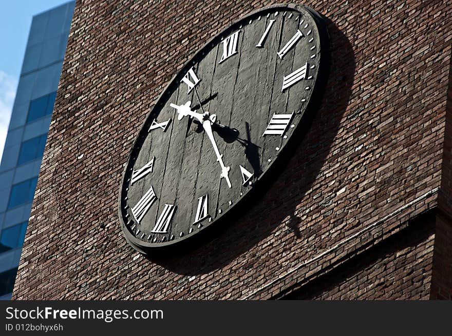 Black clock face on brick with roman numerals