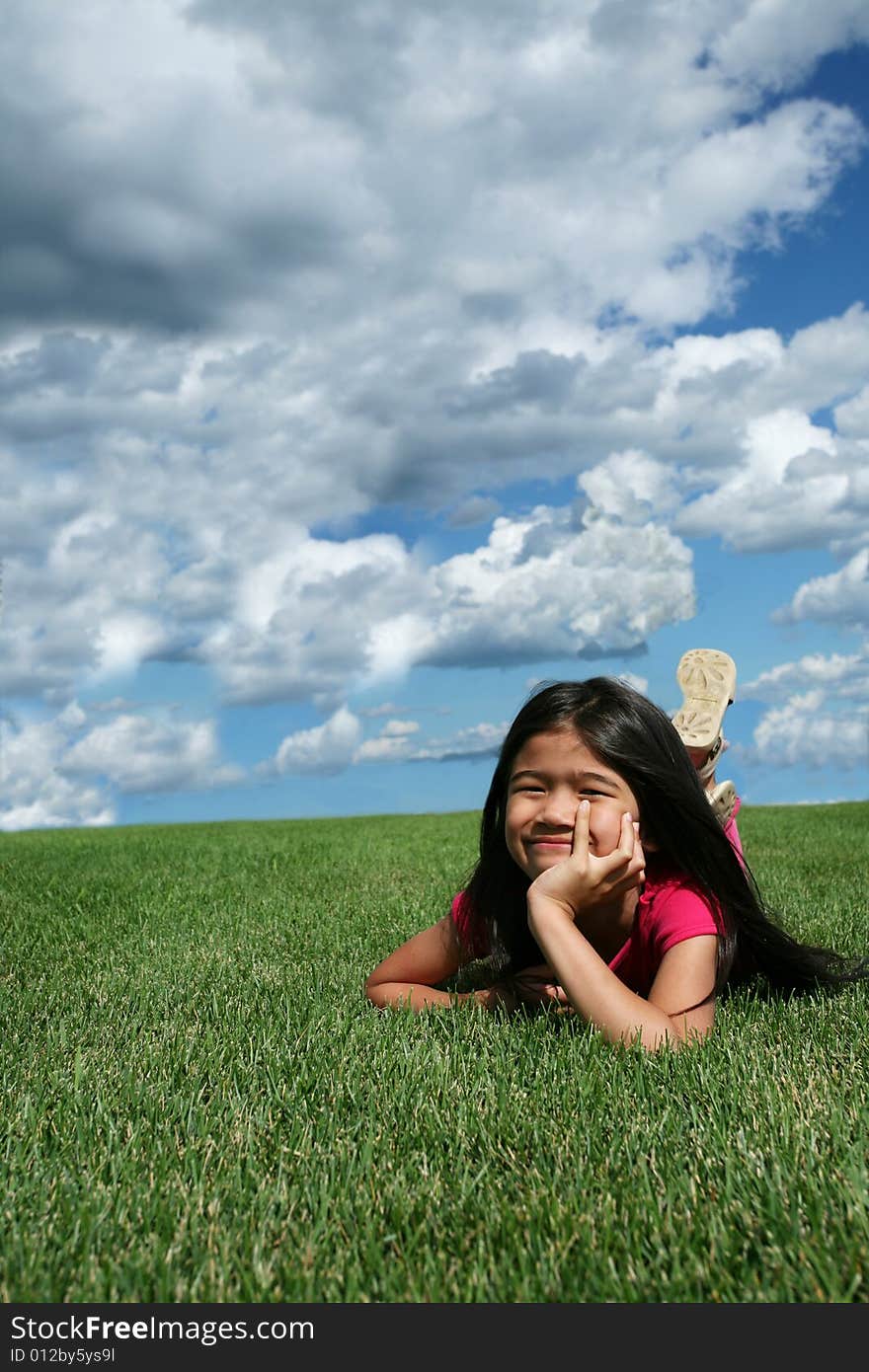 Little girl lying on grass in summer