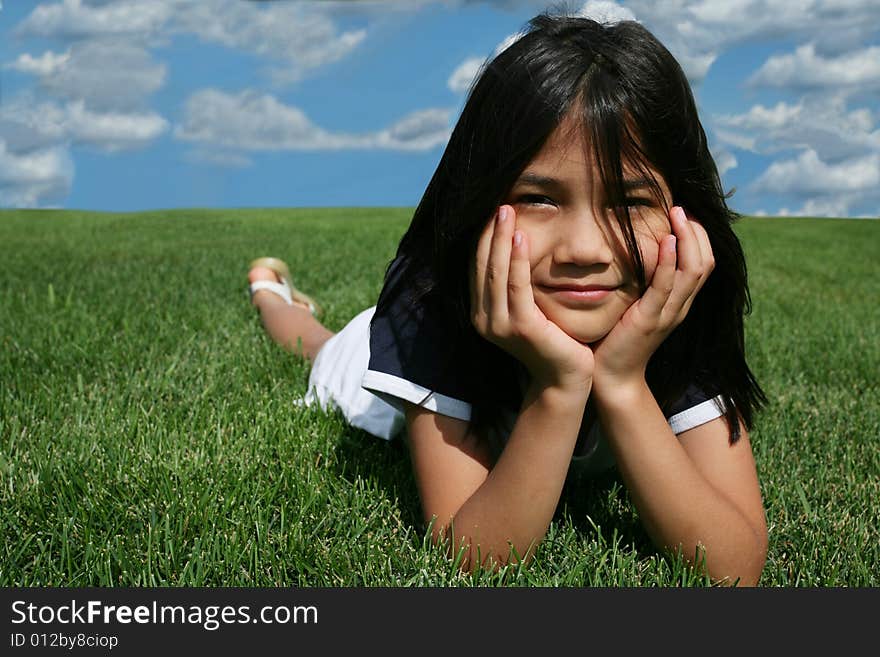 Little girl lying on grass in summer