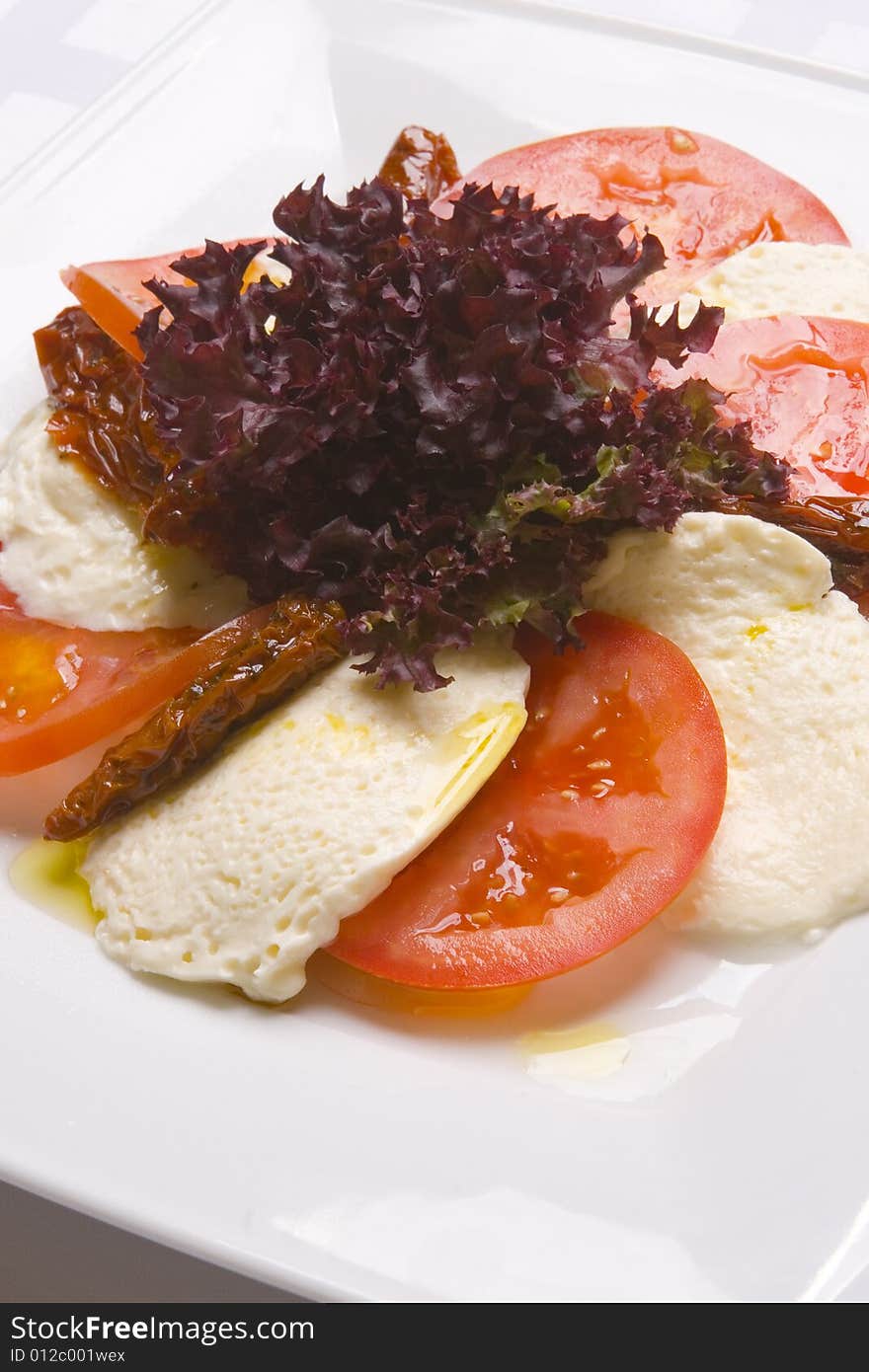 Mozzarella with tomatoes on white plate