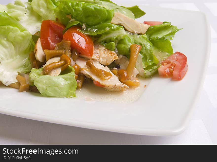 Salad with vegetables, herbs and mushrooms on white plate