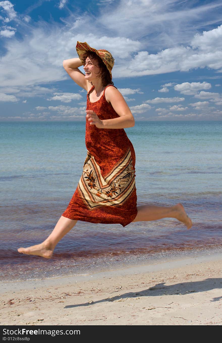 Girl in hat running at sea beach