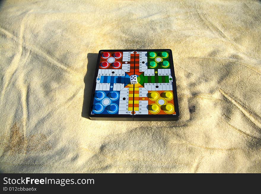 Parcheesi prepared on a yellow towel at the beach. Parcheesi prepared on a yellow towel at the beach