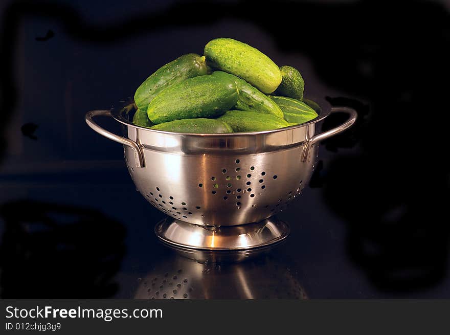 Basin with the cucumbers against the black background