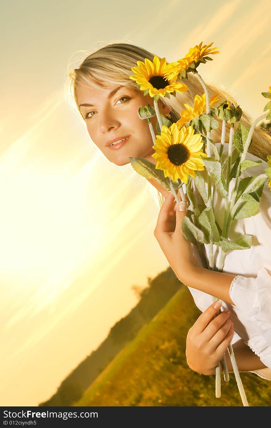 Young beautiful woman with a bouquet of sunflowers in the field at sunset. Young beautiful woman with a bouquet of sunflowers in the field at sunset