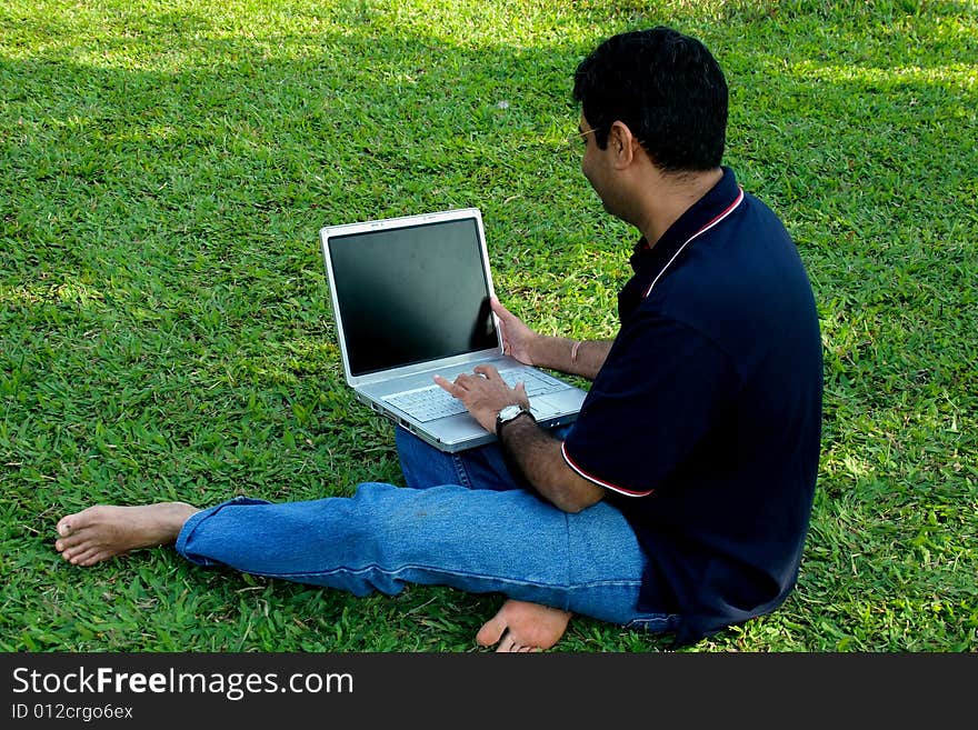 A guy enjoying his laptop while relaxing himself on the lawn. A guy enjoying his laptop while relaxing himself on the lawn.