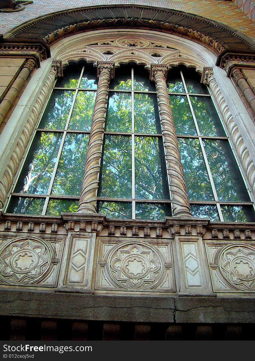 Age-old building. Florid columns. Green trees are reflected in window. Age-old building. Florid columns. Green trees are reflected in window.