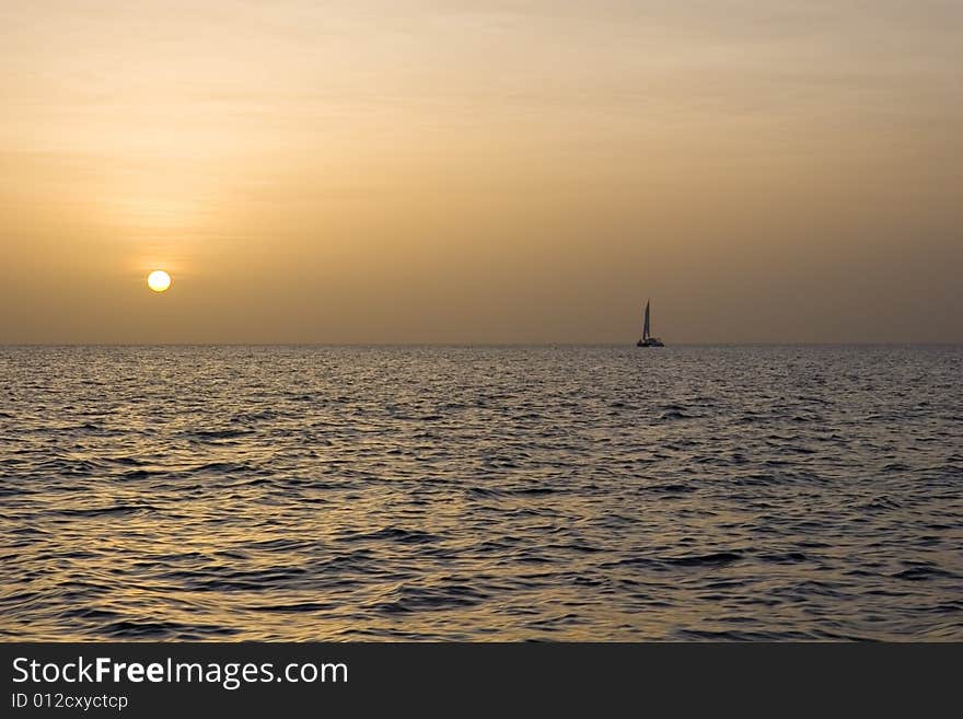 A sailboat on the horizon at sunset. A sailboat on the horizon at sunset