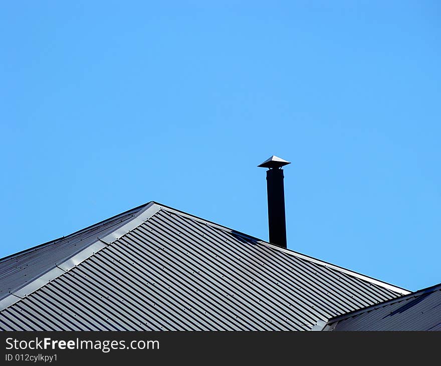 Roof and stove pipe on a background of blue sky. Space for text. Roof and stove pipe on a background of blue sky. Space for text.