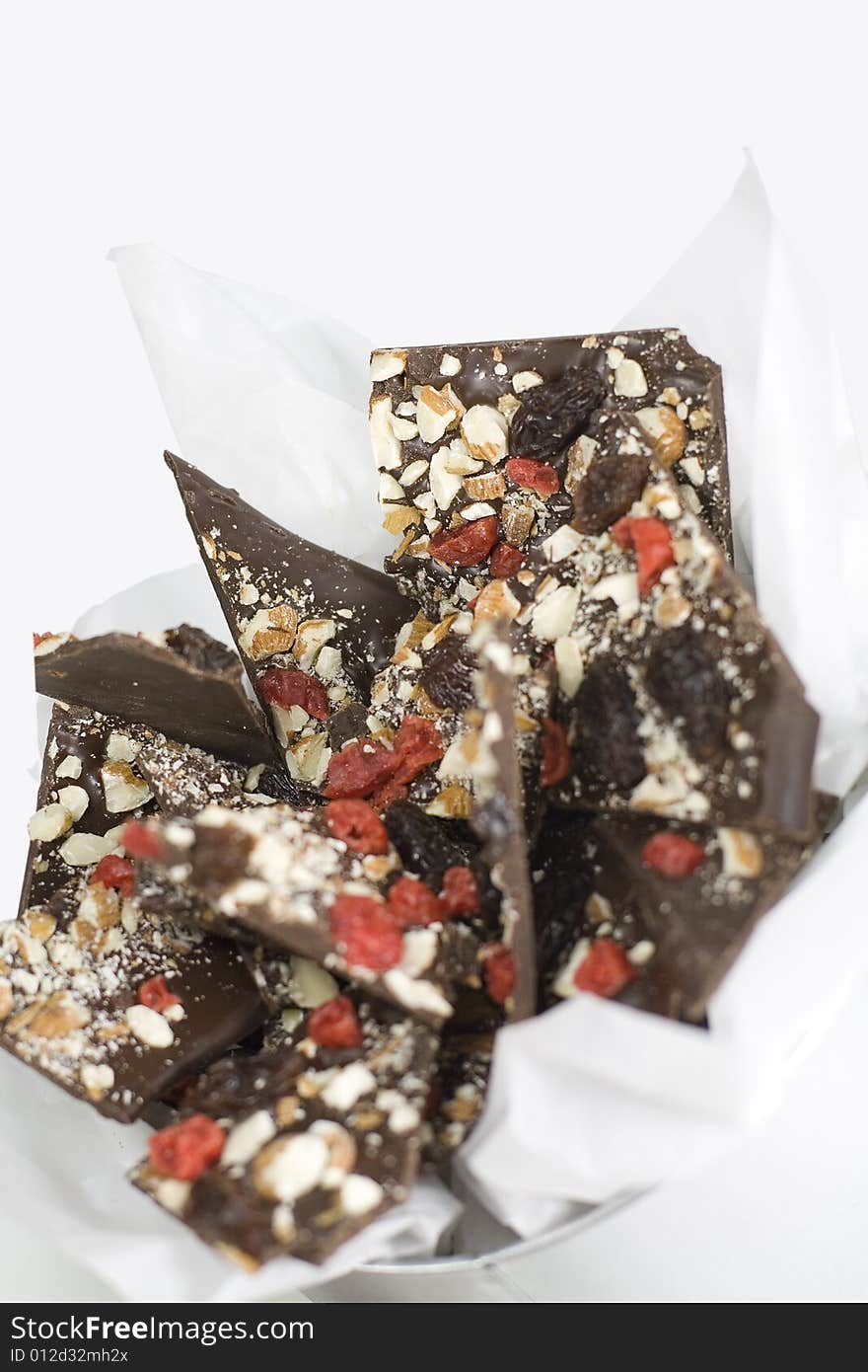 Metal box full of chocolate slices with berries and nuts closeup