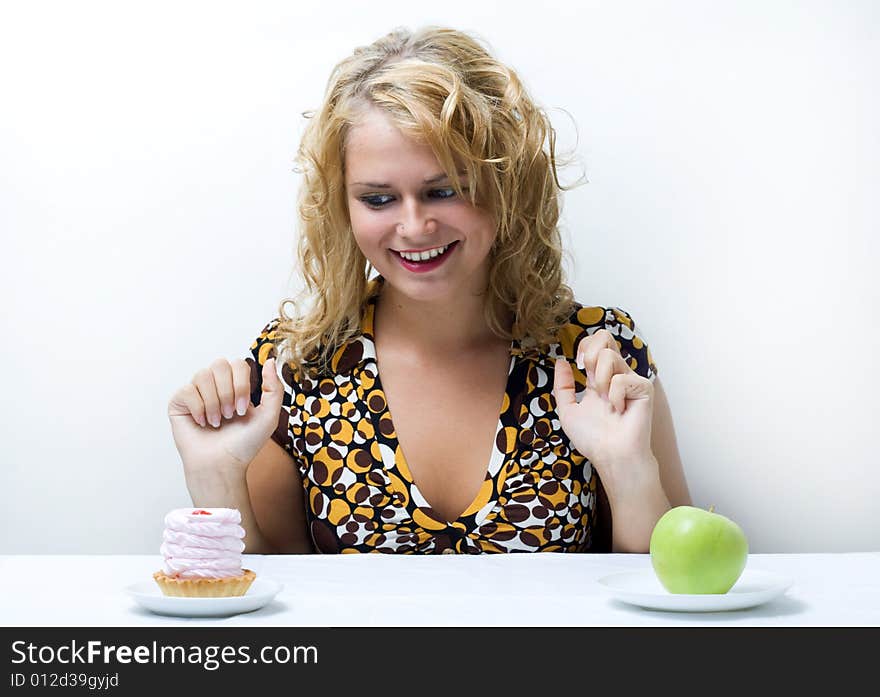 Young cute girl making choice between apple and cake. Young cute girl making choice between apple and cake.