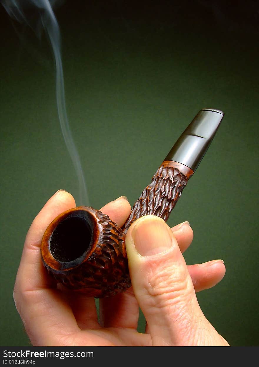 Close-up of a man's hand holding a decoratively-carved tobacco pipe. Close-up of a man's hand holding a decoratively-carved tobacco pipe.