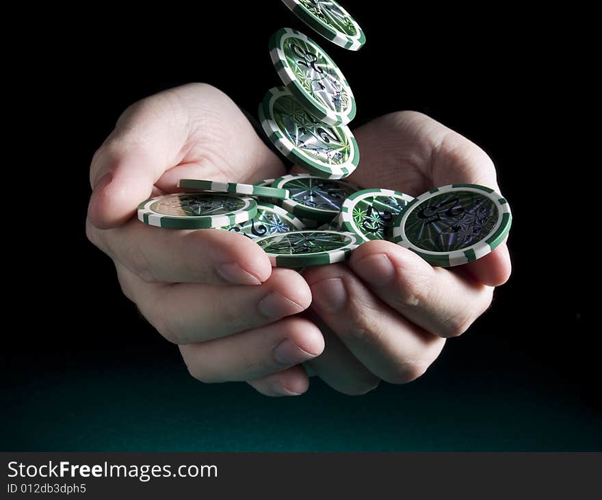 Several green twenty five valued chips falling on a pair of hands isolated over a black background. Several green twenty five valued chips falling on a pair of hands isolated over a black background.